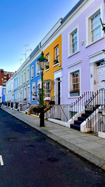 The image depicts a row of colorful terraced houses in Notting Hill, London, with facades painted in pastel shades of blue, yellow, and lavender. Each house features white-framed sash windows, black w