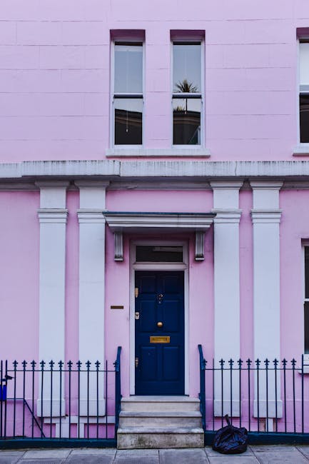 The image depicts a row of colorful terraced houses in Notting Hill, London, with facades painted in pastel shades of blue, yellow, and lavender. Each house features white-framed sash windows, black w